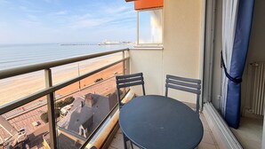 A balcony with a view of the beach, a table, and two chairs. - Beachfront Apartment with Balcony, Sleeps 4, 2 Stars (Les Sables-d'Olonne)