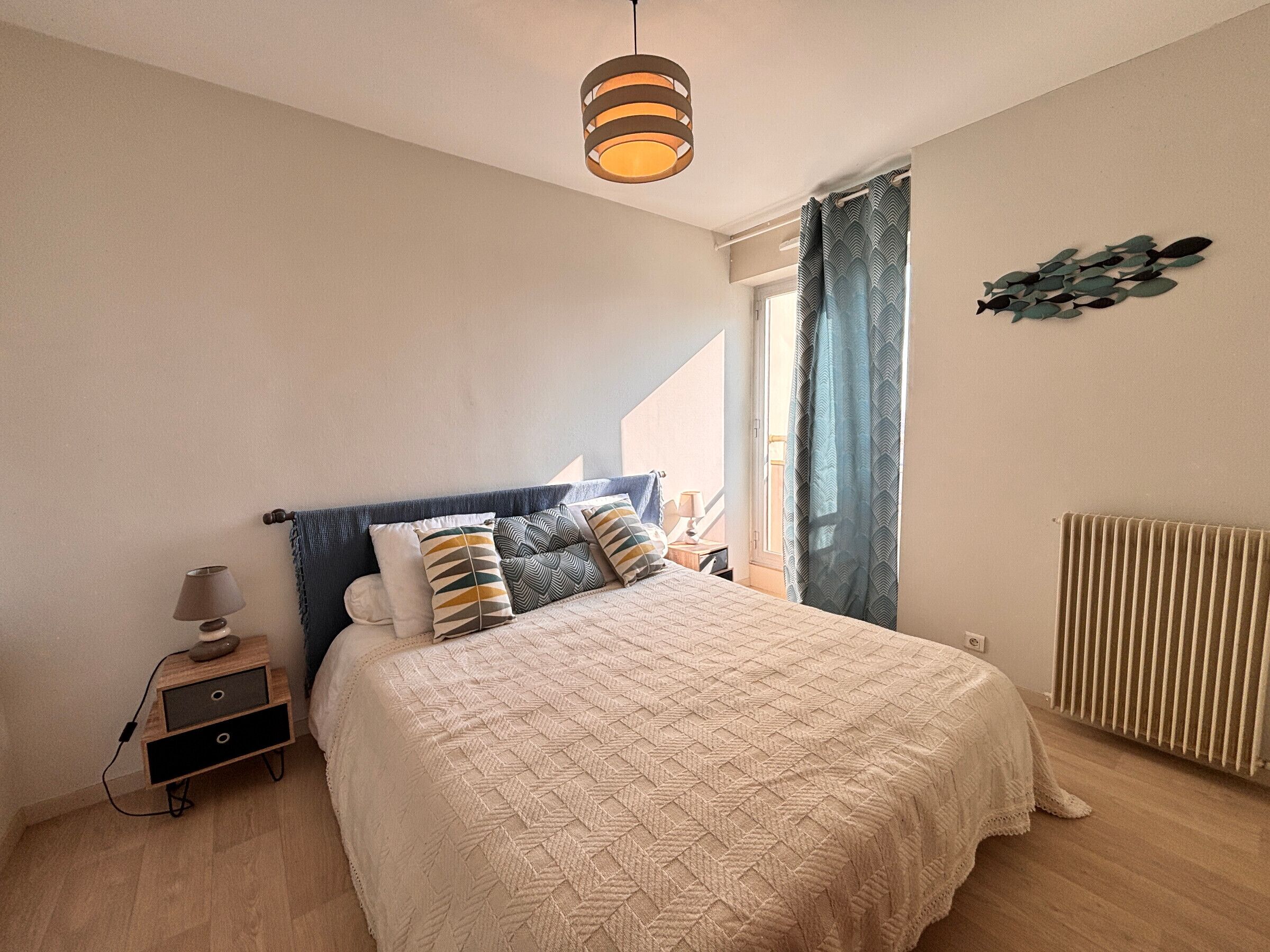 Een slaapkamer met een bed, nachtkastje, lamp en een radiator.