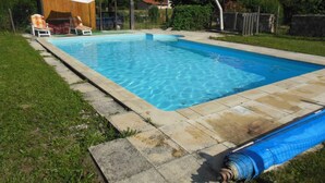 Une piscine rectangulaire à l’eau d’un bleu limpide, entourée d’une terrasse en pierre et d’une pelouse.
