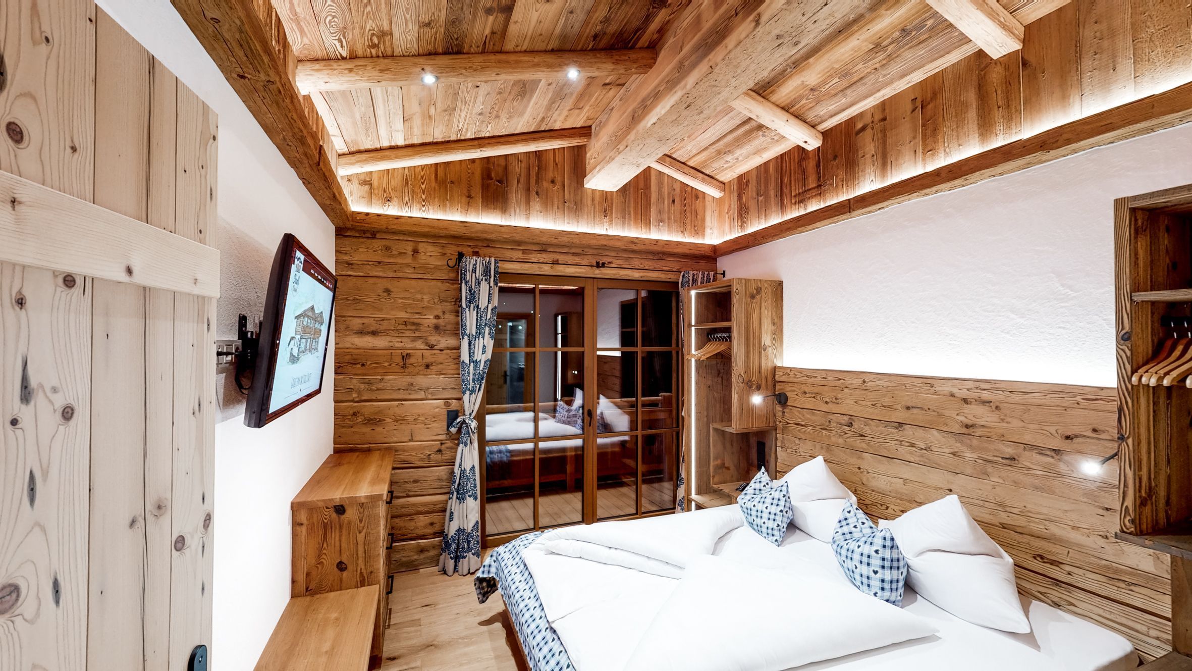 Een houten interieur met een bed, een bankje en een garderobe.