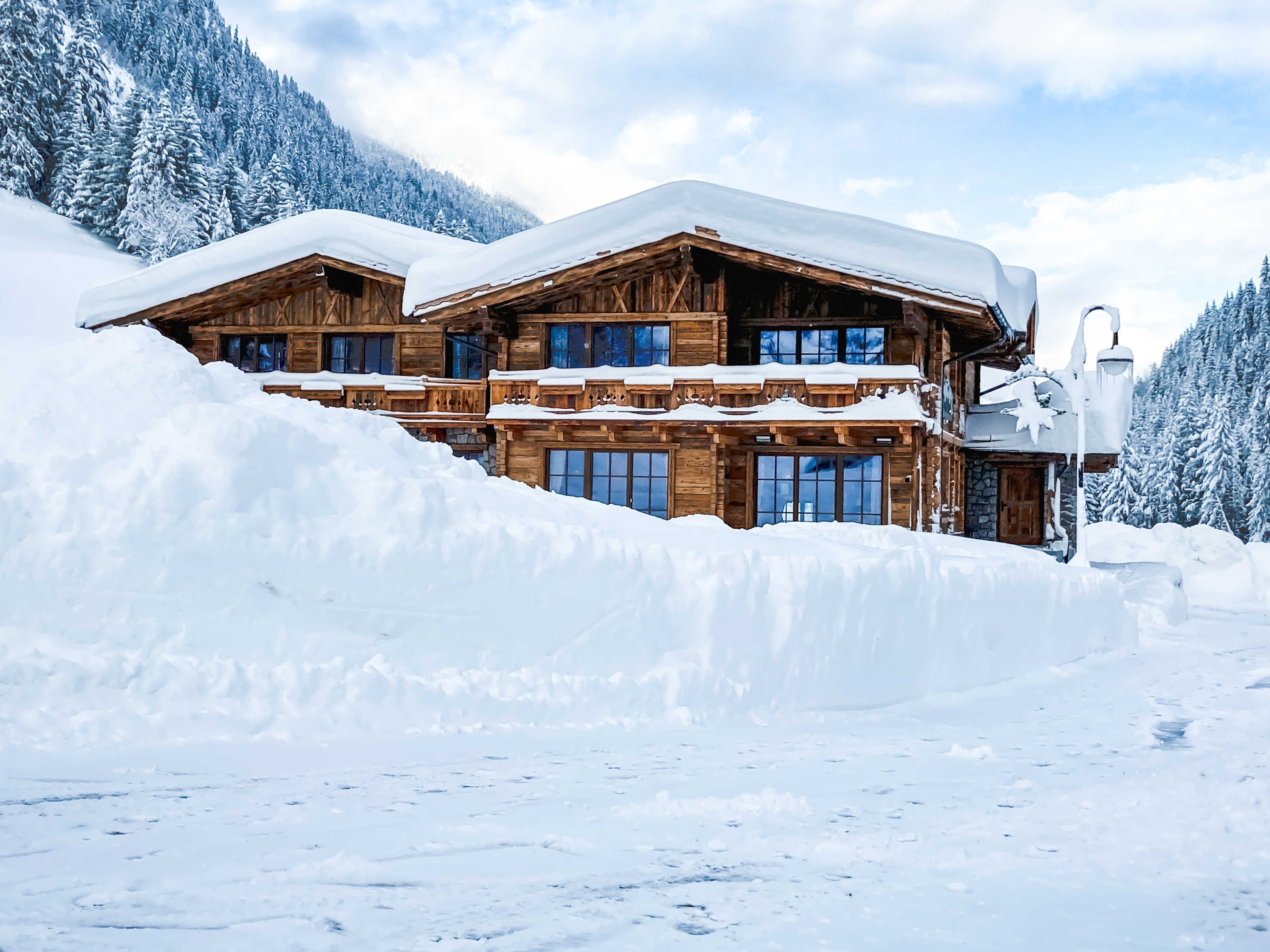Een houten chalet met meerdere balkons, omringd door besneeuwde bergen.