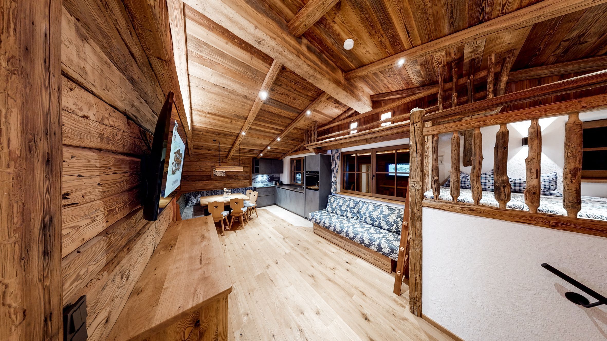 Un intérieur en bois comprenant un coin repas, une cuisine et un espace détente près d’une fenêtre.