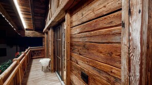 Un mur extérieur en bois avec une terrasse en bois menant à une porte.