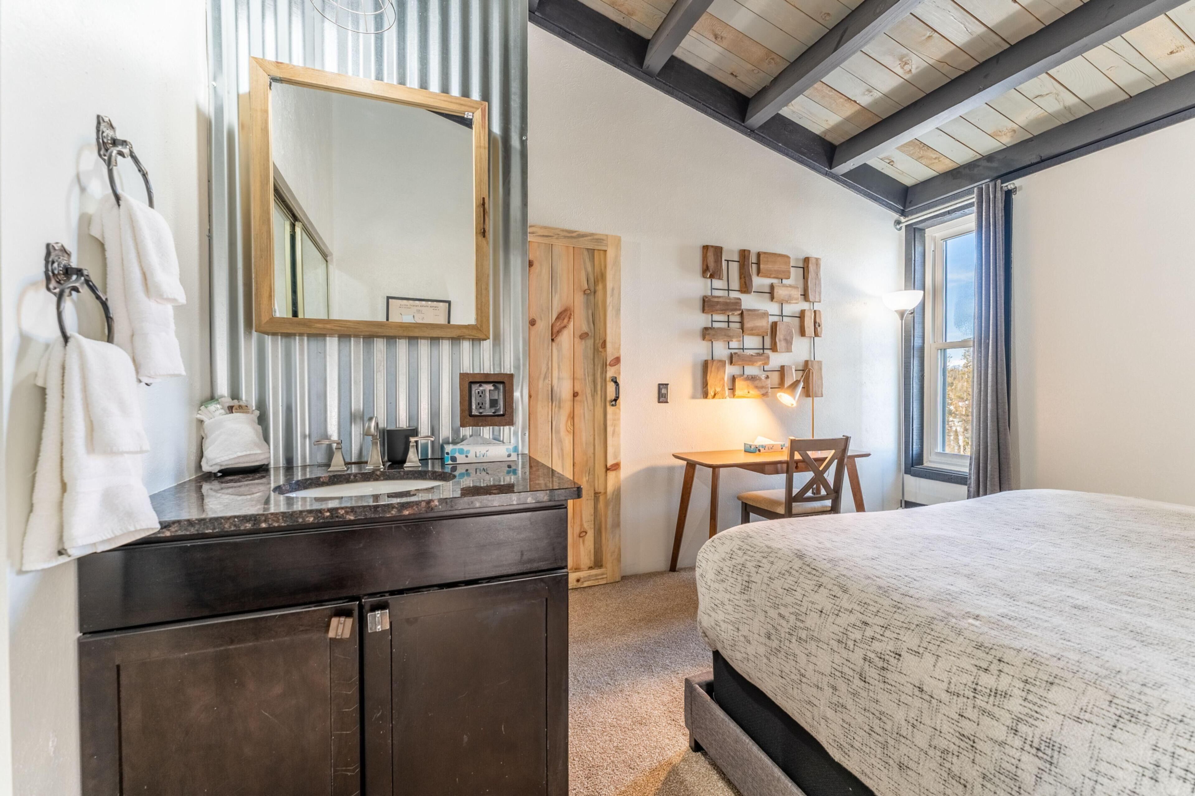 Un dormitorio con una cama grande, un aparador, un espejo, una puerta de madera y una ventana.