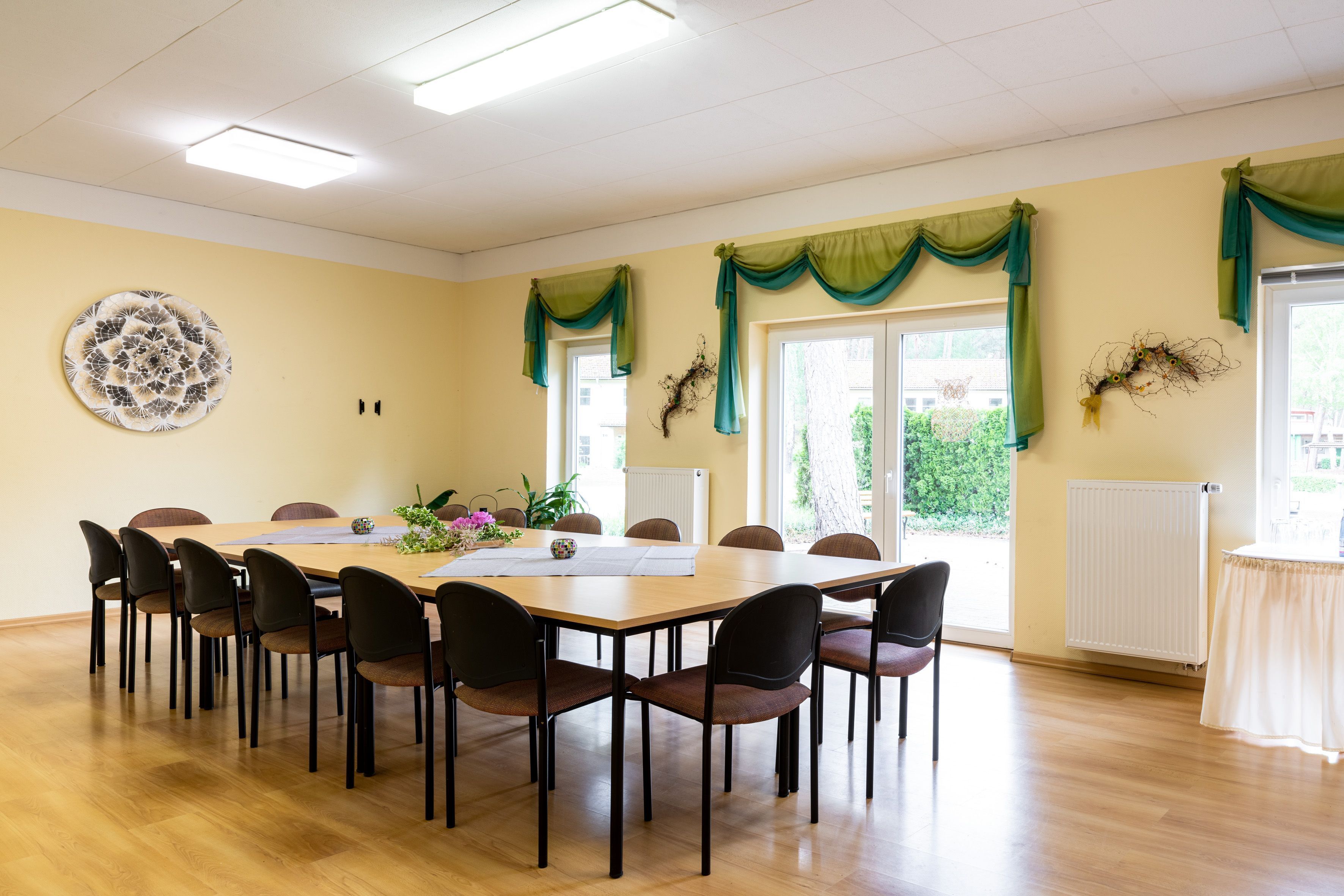 Ein Konferenzraum mit einem langen Tisch, Stühlen und einem Wanddekor.