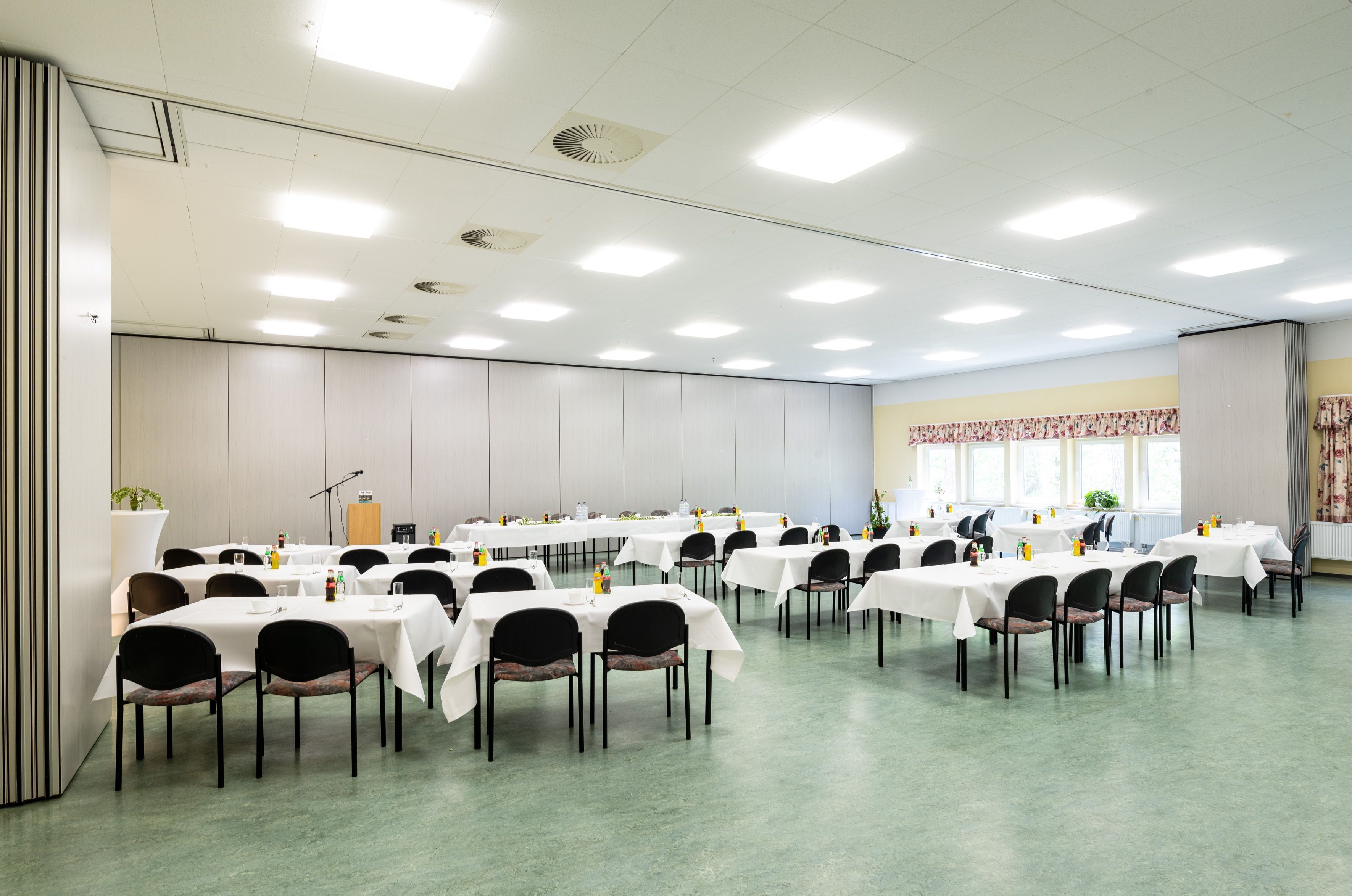 A conference room with multiple tables and chairs, equipped with microphones and nameplates, suggesting a formal meeting or event setting.
