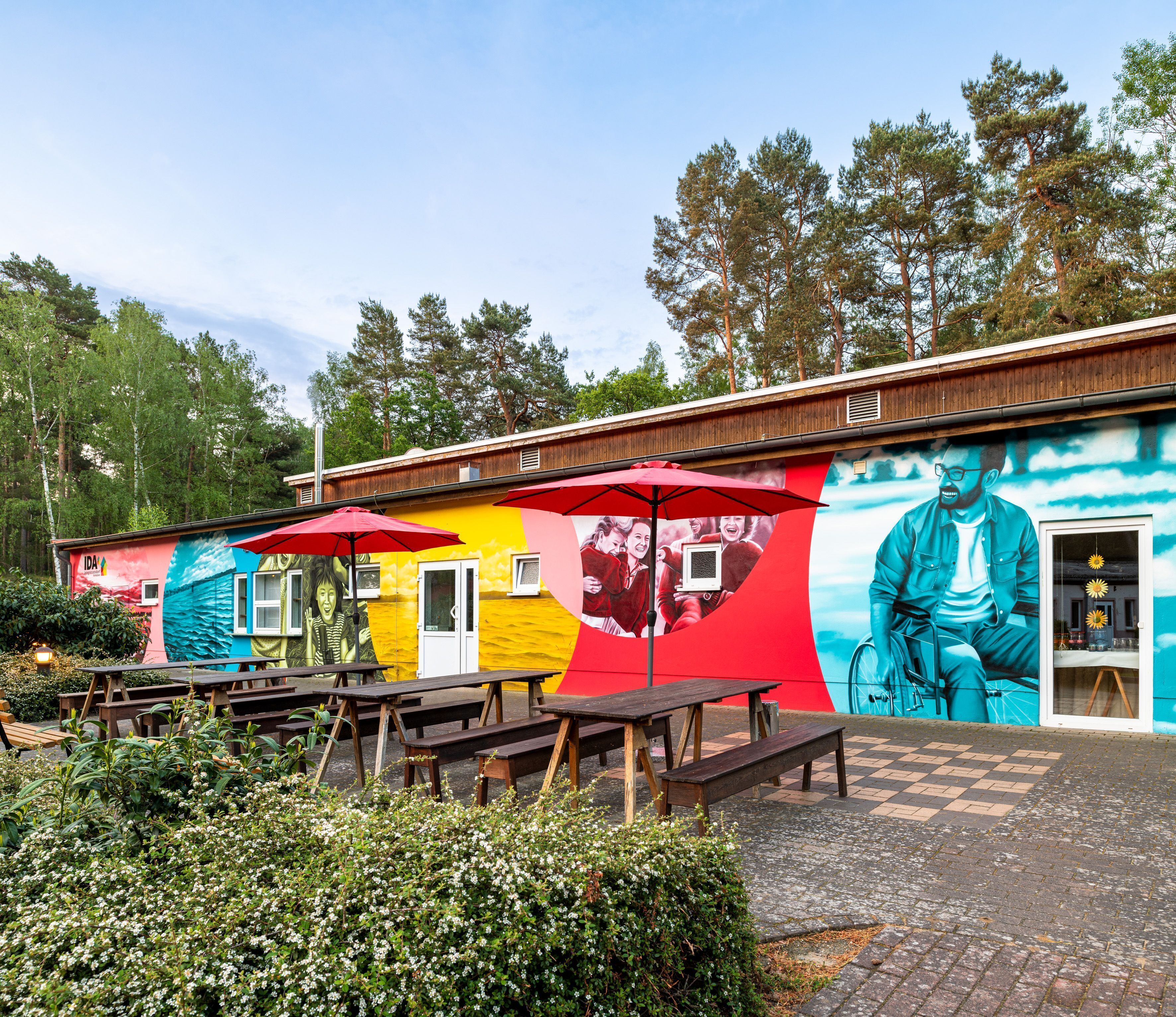 A colorful mural on a building with outdoor seating and a bicycle.