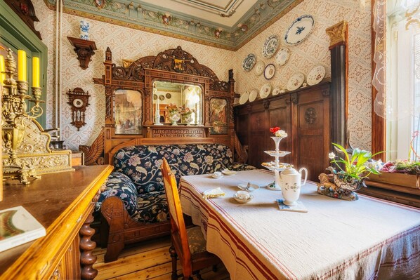 A room with a wooden bench, a table set with tea service, and a mirror with a floral pattern.