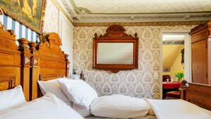 Habitación de hotel elegante con una cama grande, cabecera de madera, un espejo y papel tapiz estampado.