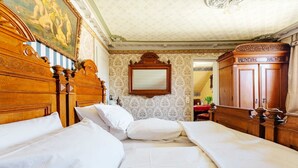 Habitación de hotel con dos camas, cabecera de madera, espejo y armario.