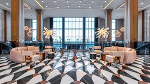 A spacious lobby with a geometric marble floor, large seating areas, and a view of the city through large windows. - Lago Hotel (Manavgat)