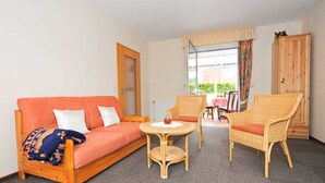A room with a sofa, two chairs, a small table, a wardrobe, and a window with curtains. - Vacation apartment Riegstra in Esens - Holiday apartment Riegstra (Esens)