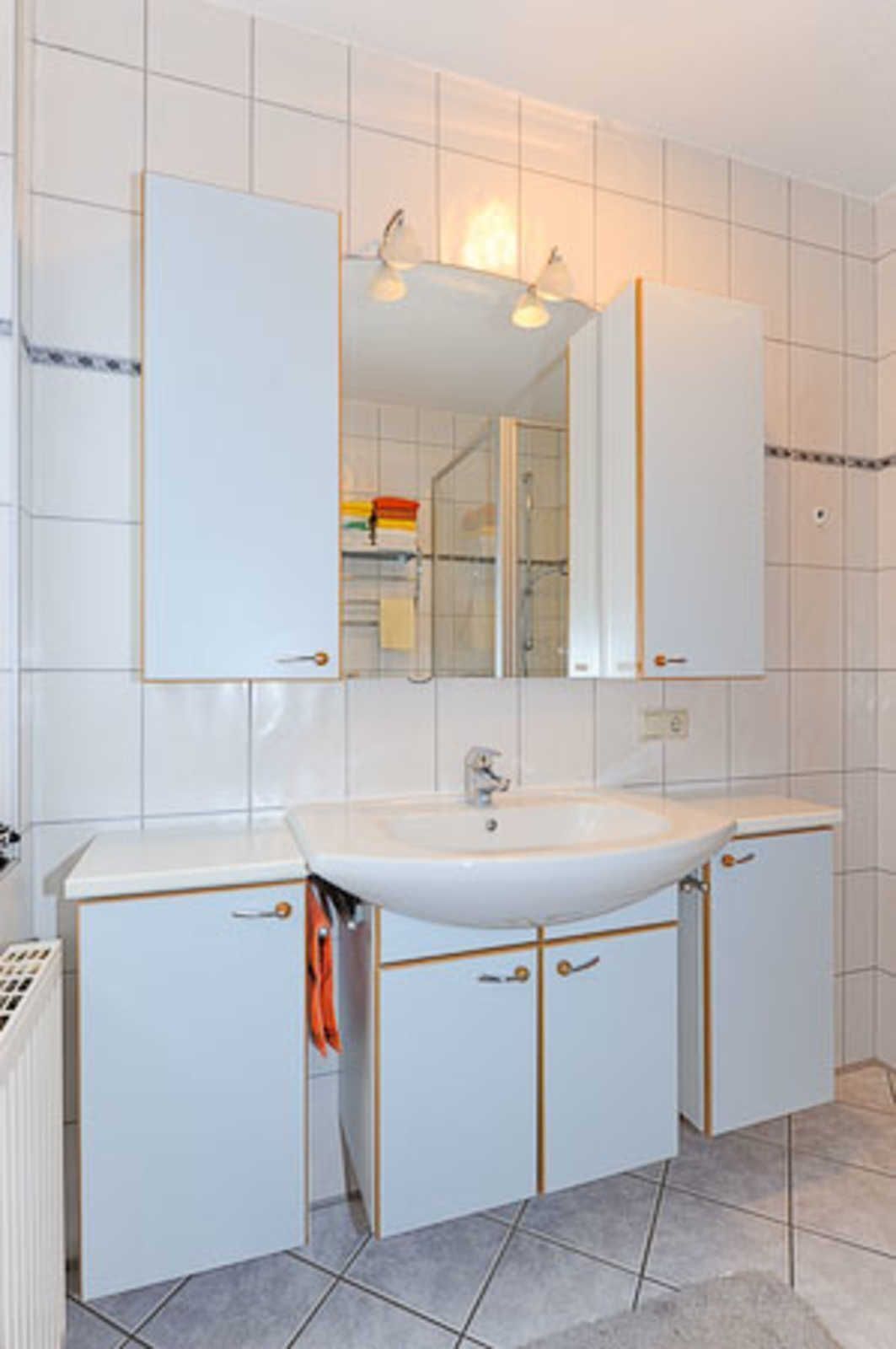 Ein Badezimmer mit Waschbecken, Spiegel und Schränken.