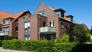 A multi-story residential building with brick exterior, a balcony, and a clear blue sky. - Vacation apartment Riegstra in Esens - Holiday apartment Riegstra (Esens)