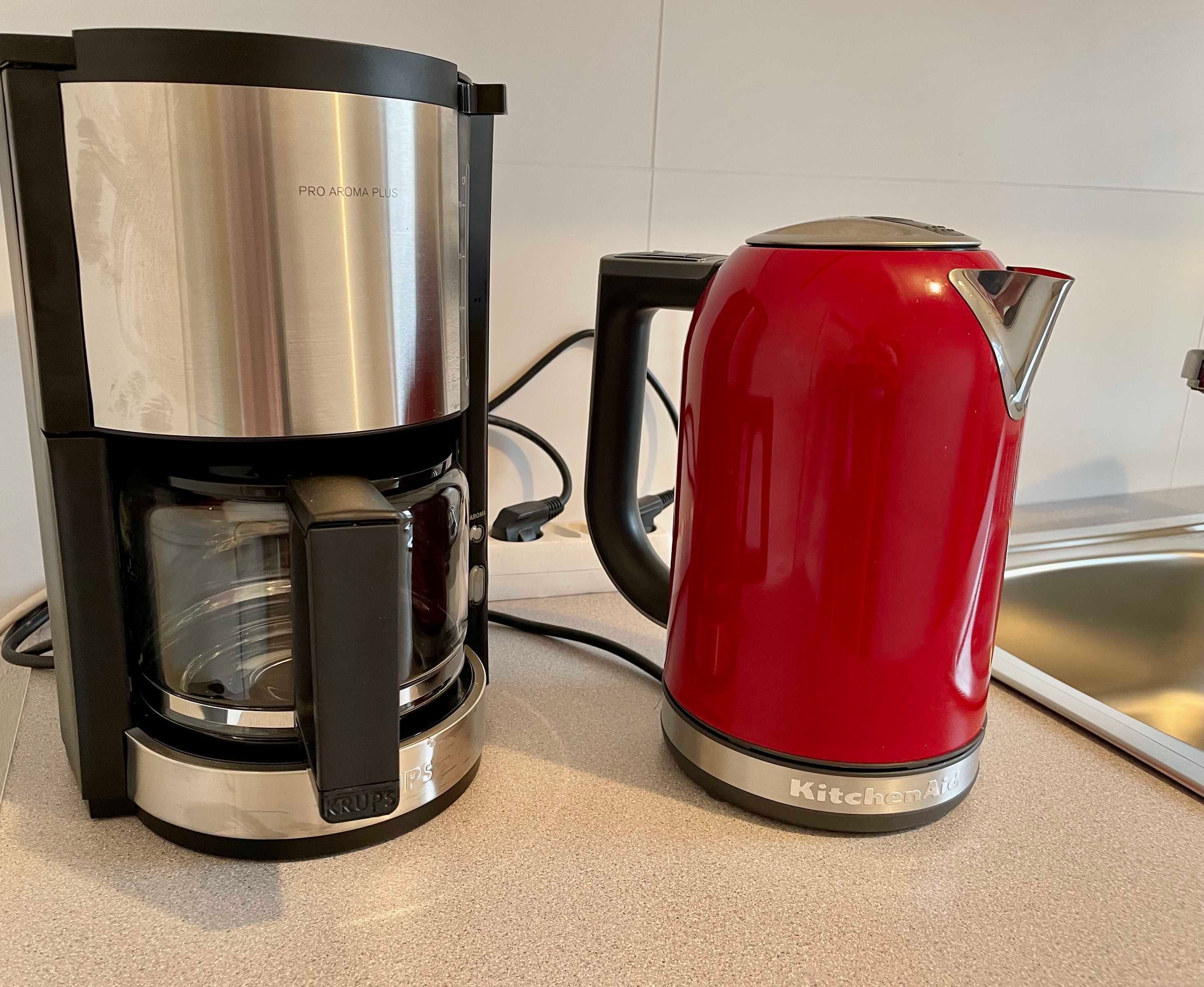 A coffee maker and a red kettle on a kitchen counter.