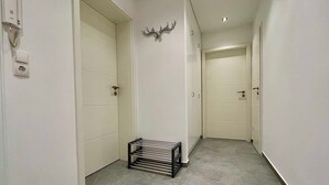 A narrow hallway with white walls, a metal rack, and a mounted deer head. - Bergfürst bed linen bookable - Bergfürst (Bad Harzburg)