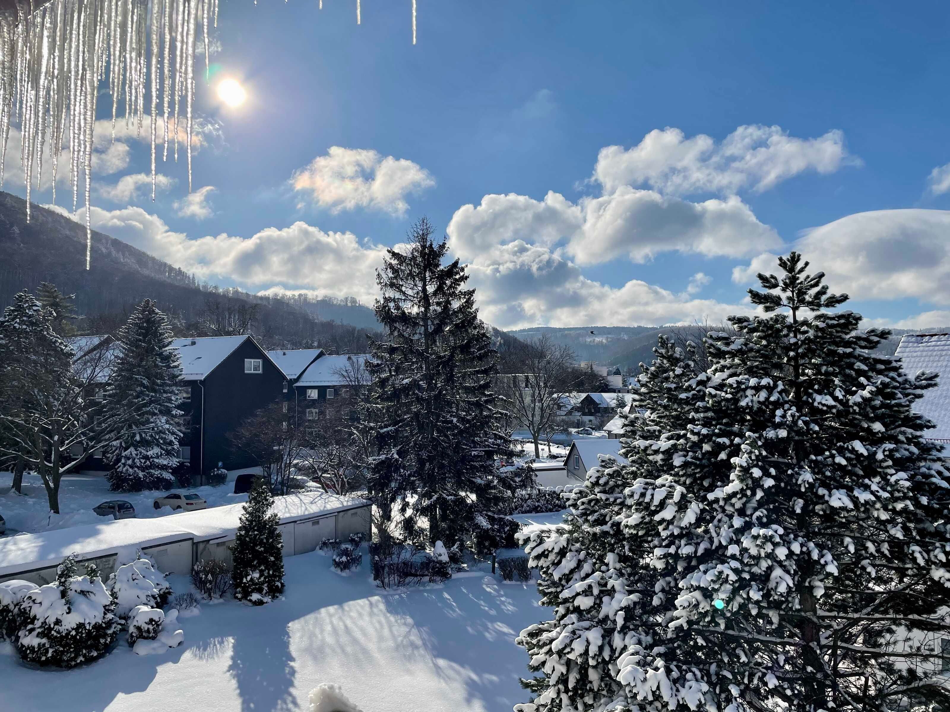 A snow-covered landscape with a building, trees, and a clear sky.