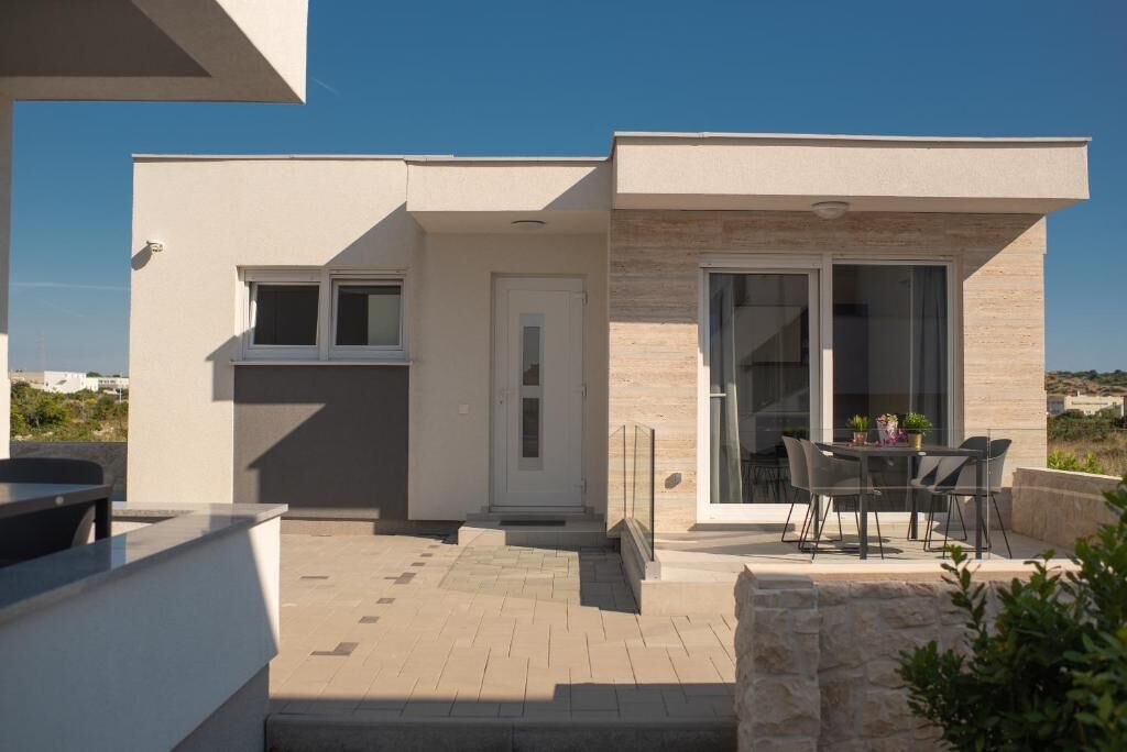 Una casa moderna de dos pisos con un patio, una mesa de comedor y sillas.