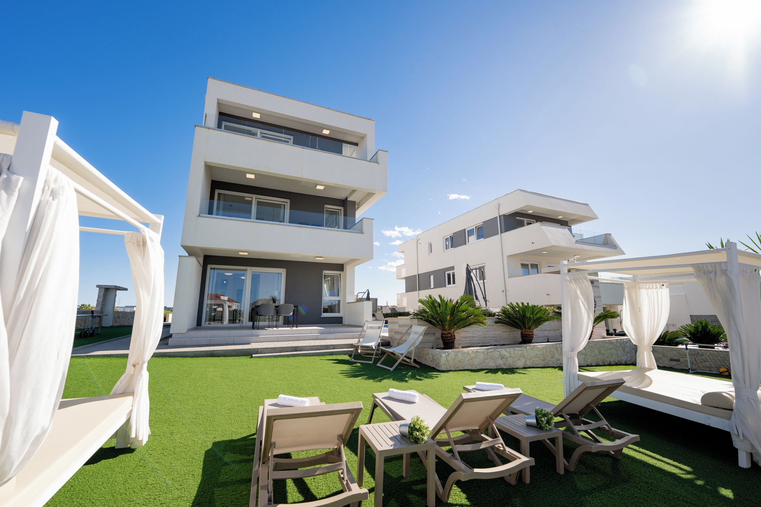 Een modern, tweelaags gebouw met een balkon en een terras.