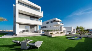Un bâtiment moderne à deux étages, doté d’un toit plat, d’une pelouse bien entretenue et d’un espace extérieur aménagé pour s’asseoir.