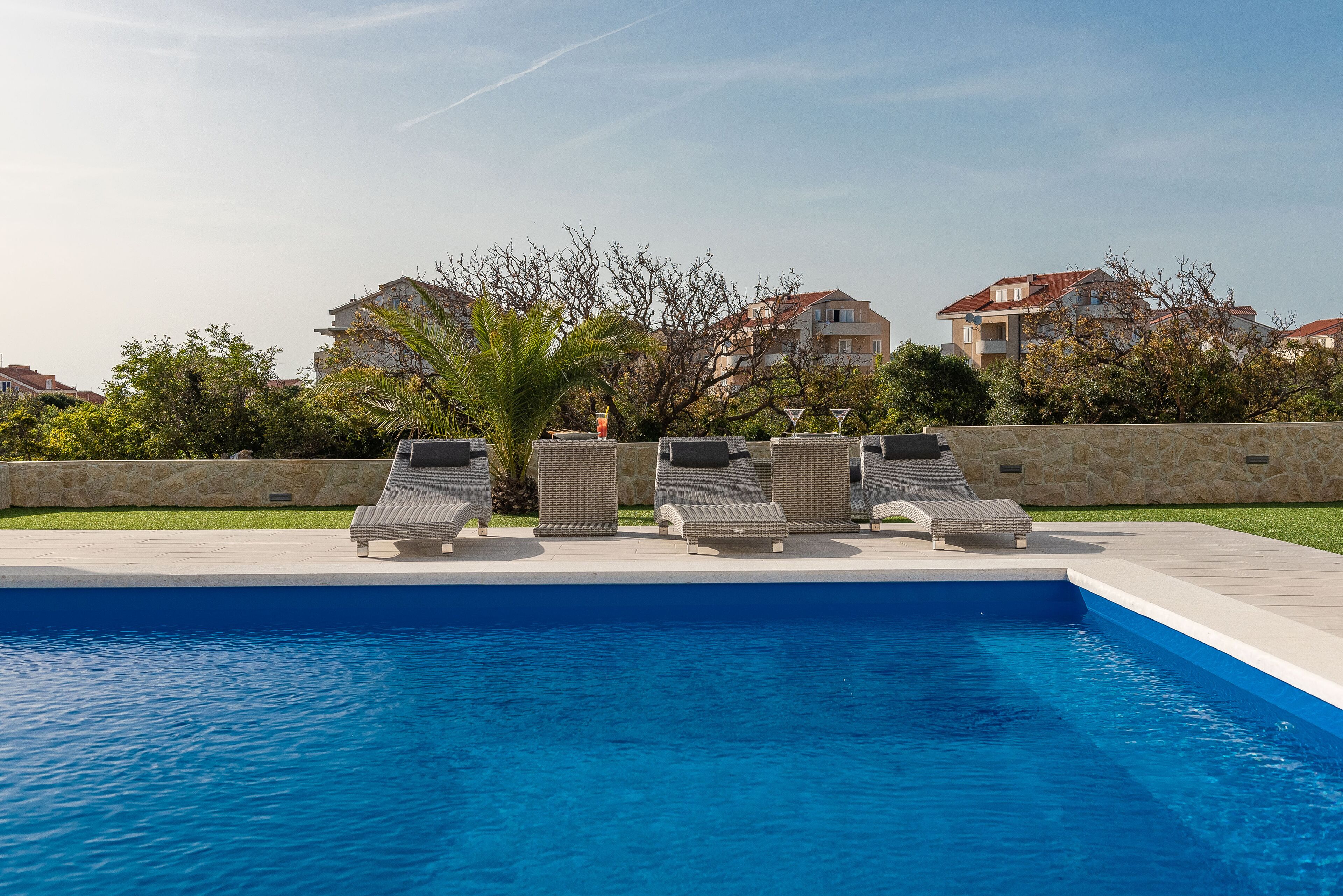 A swimming pool with lounge chairs and a stone wall.
