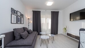 Un salon moderne avec un canapé gris, un téléviseur à écran plat, une table basse et un téléviseur fixé au mur.