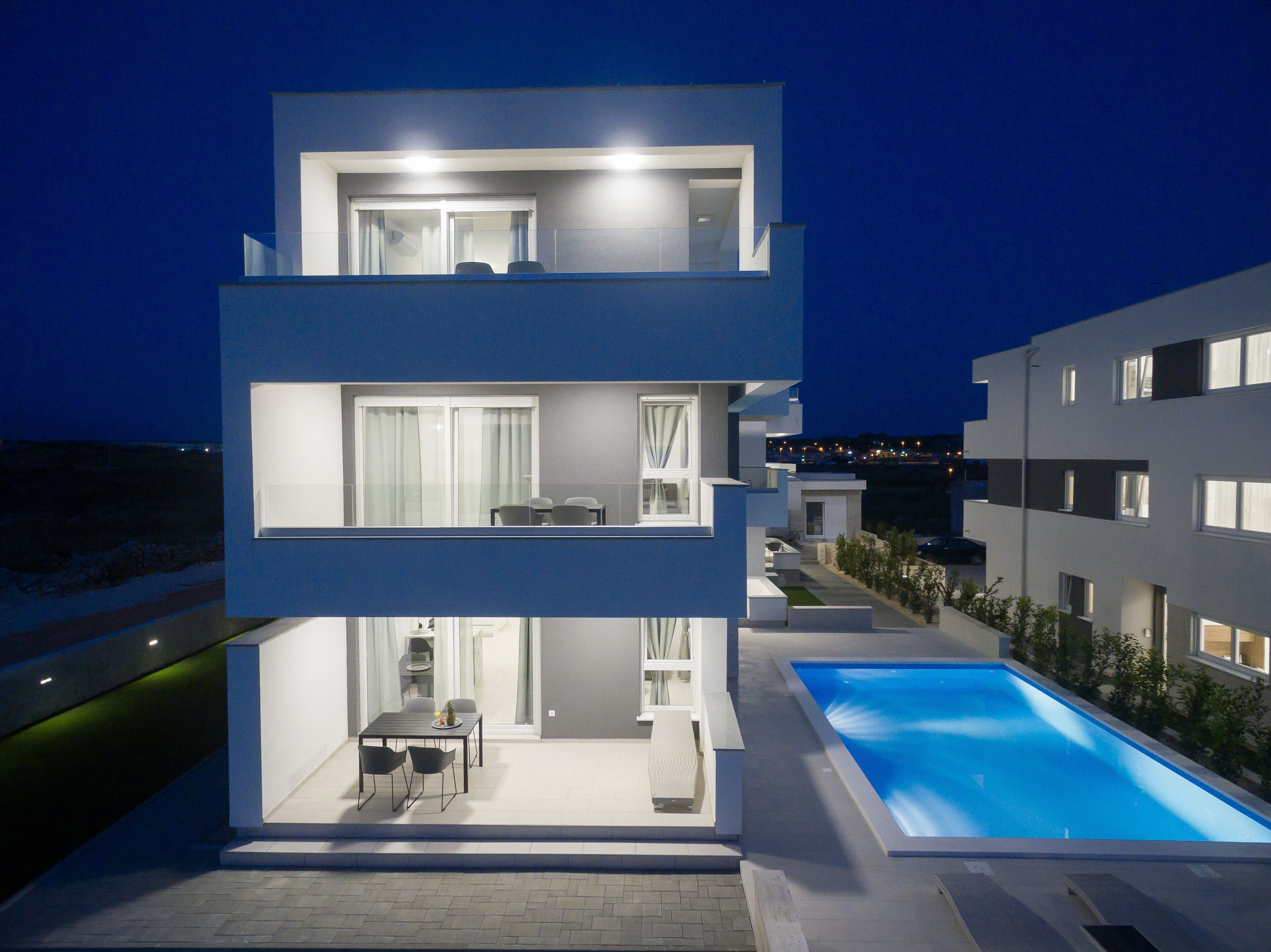 A modern multi-story building with a rooftop pool and outdoor seating area.