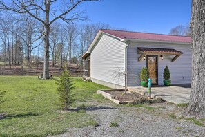 Situated in a rural setting, this charming house features a front porch with a door and potted plants.
