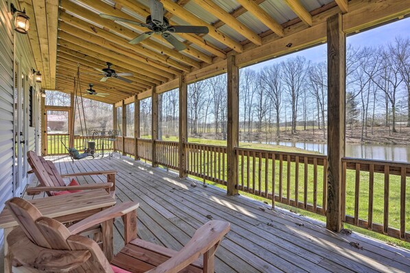 Relax on the deck with a serene lake view, surrounded by lush trees.