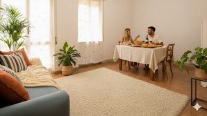 A cozy living room with a sofa, a dining table with two people, and potted plants. - Appartamento Kennedy 1 (Diano Marina)