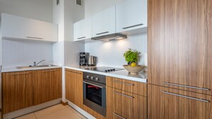 Eine moderne Küche mit Holzschränken, einem Edelstahlbackofen und einer Kaffeemaschine.