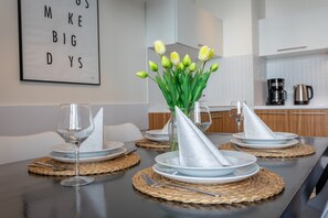 A dining table set with plates, cutlery, and a vase with flowers. - Beachfront vacation apartment, vacation on the island of Usedom, PLATAN IV Apartment (Swinoujscie)
