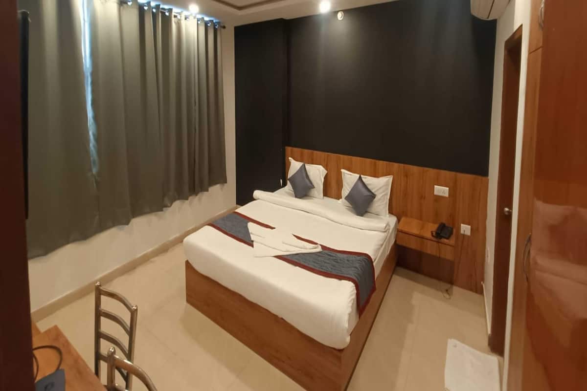 A bedroom with a bed, a ceiling fan, a nightstand, and a window with curtains.