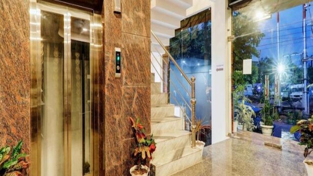 A hotel lobby with a marble reception desk, a staircase, and a glass door leading outside. - Hotel Orchid (Lucknow)