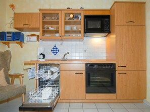 Cozinha compacta com armários de madeira, micro-ondas, forno e lava-louças.