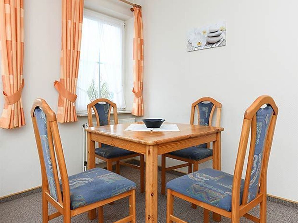 Un comedor con una mesa de madera y cuatro sillas con tapicería estampada.