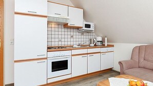 A compact kitchen with white cabinets, a microwave, a coffee maker, and a sink. - Vacation apartments in Huus Janssand in Bensersiel - Holiday apartment 1 (Esens)