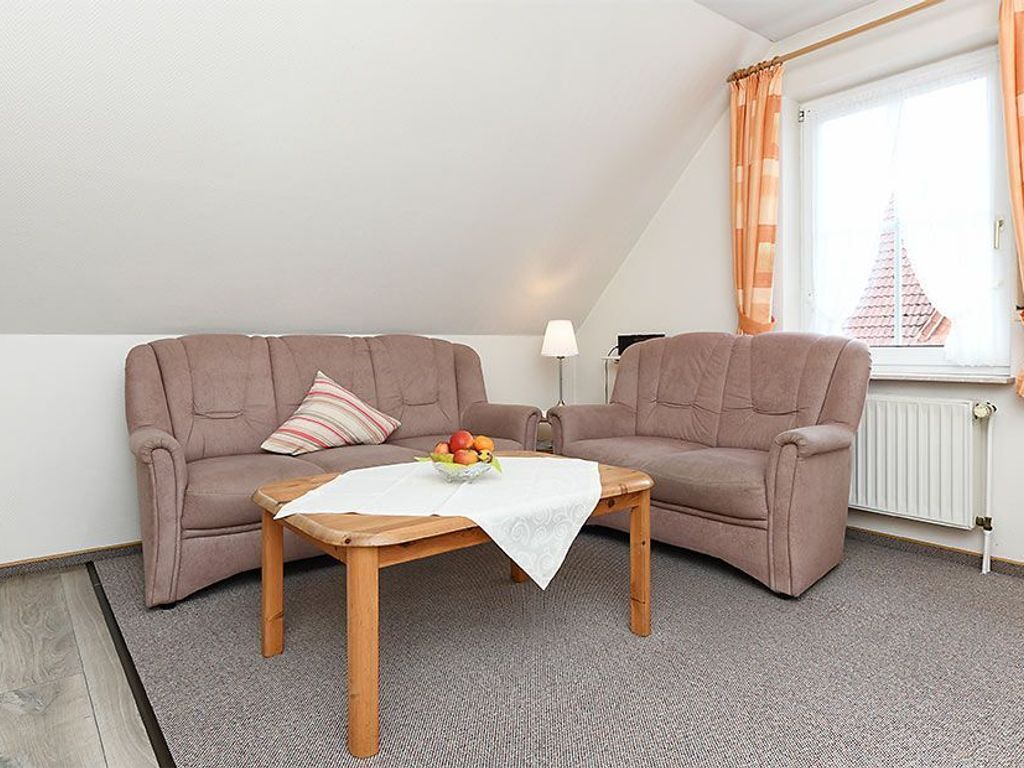 A cozy living room with a brown sofa set, a wooden coffee table with a white tablecloth, and a fruit bowl.