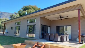 Una casa moderna con un porche cubierto, ventanas amplias y mobiliario de exterior.