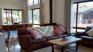Amplia sala de estar con un sofá de cuero marrón, una mesa de centro de madera y un ventanal con vistas al exterior.