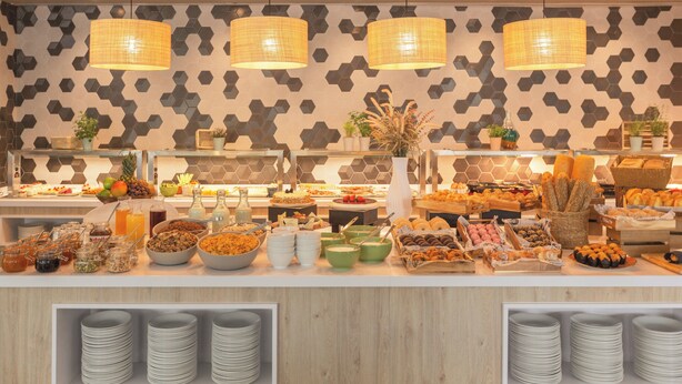 Een buffet met diverse gerechten en een behang met patroon op de achtergrond.
