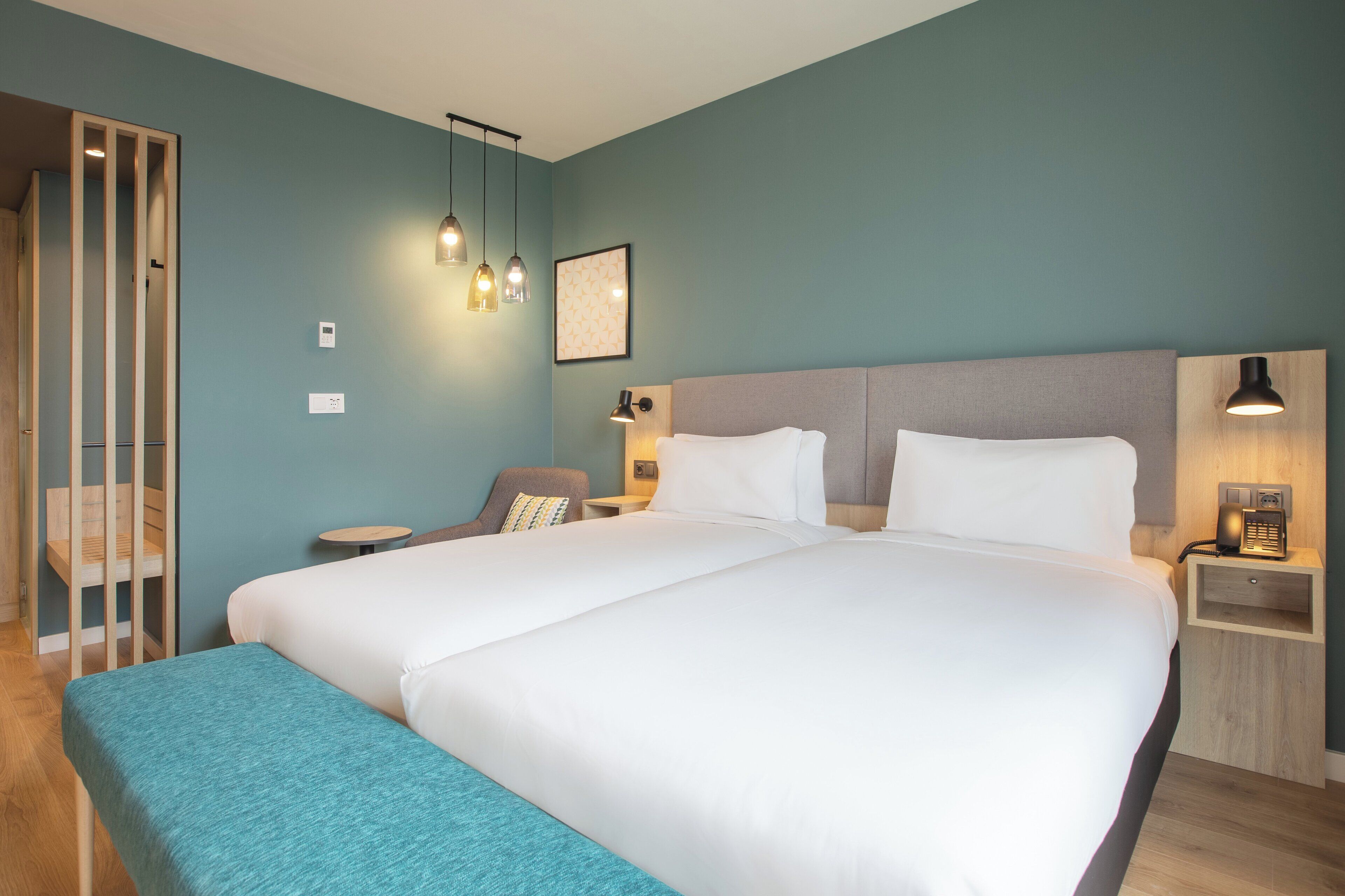 Een hotelkamer met een groot bed, nachtkastjes, een stoel en een bureau.