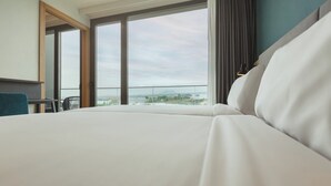 A hotel room with a large bed, a desk, and a view of the city through large windows. - Holiday Inn Barcelona-Sant Cugat by IHG (Sant Cugat del Valles)