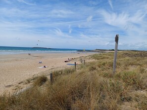 A beach with a sandy shore, a wooden fence, and a grassy area.