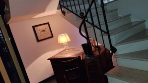 Una escalera con barandilla de vidrio, un escritorio con lámpara y un cuadro en la pared.
