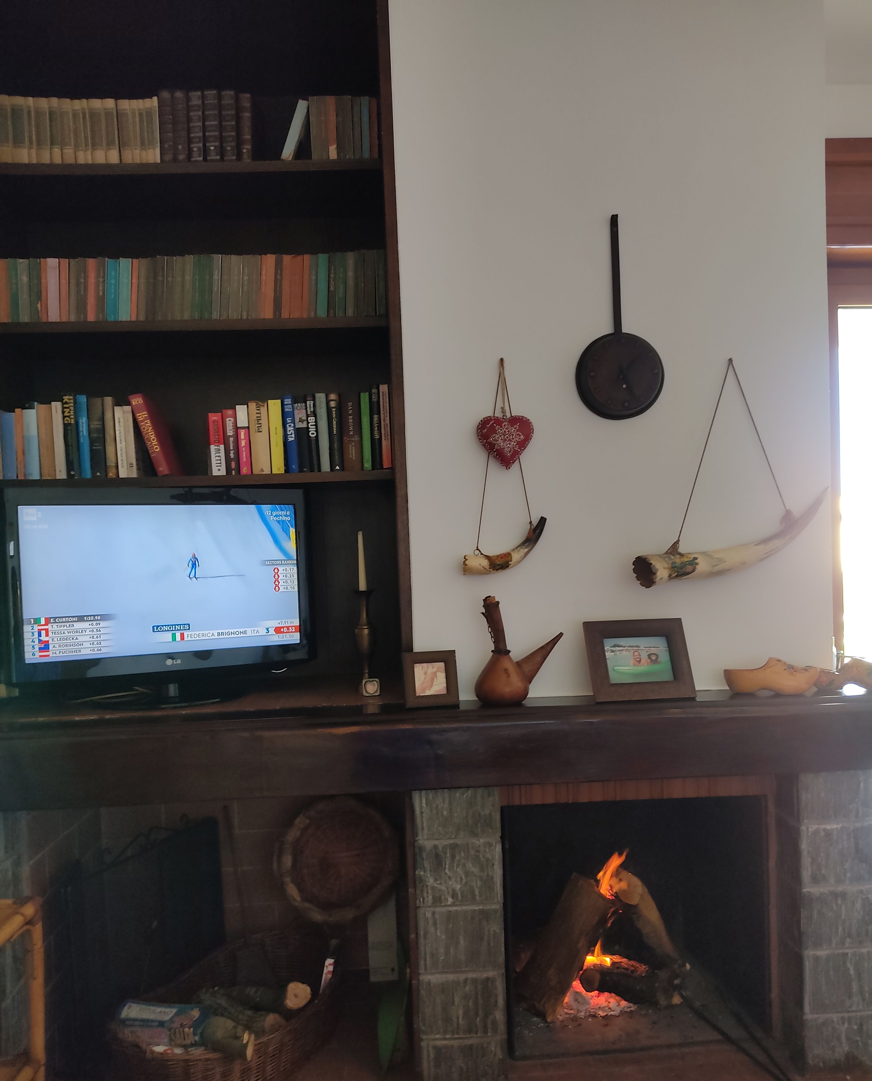 Ein Wohnzimmer mit Kamin, Fernseher, Bücherregal und Dekoration.