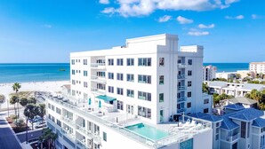 Un hotel de varios pisos con piscina en la azotea y vista a la playa y el océano.