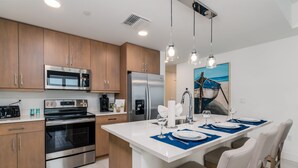 Una cocina moderna con electrodomésticos de acero inoxidable, armarios de madera e iluminación colgante.