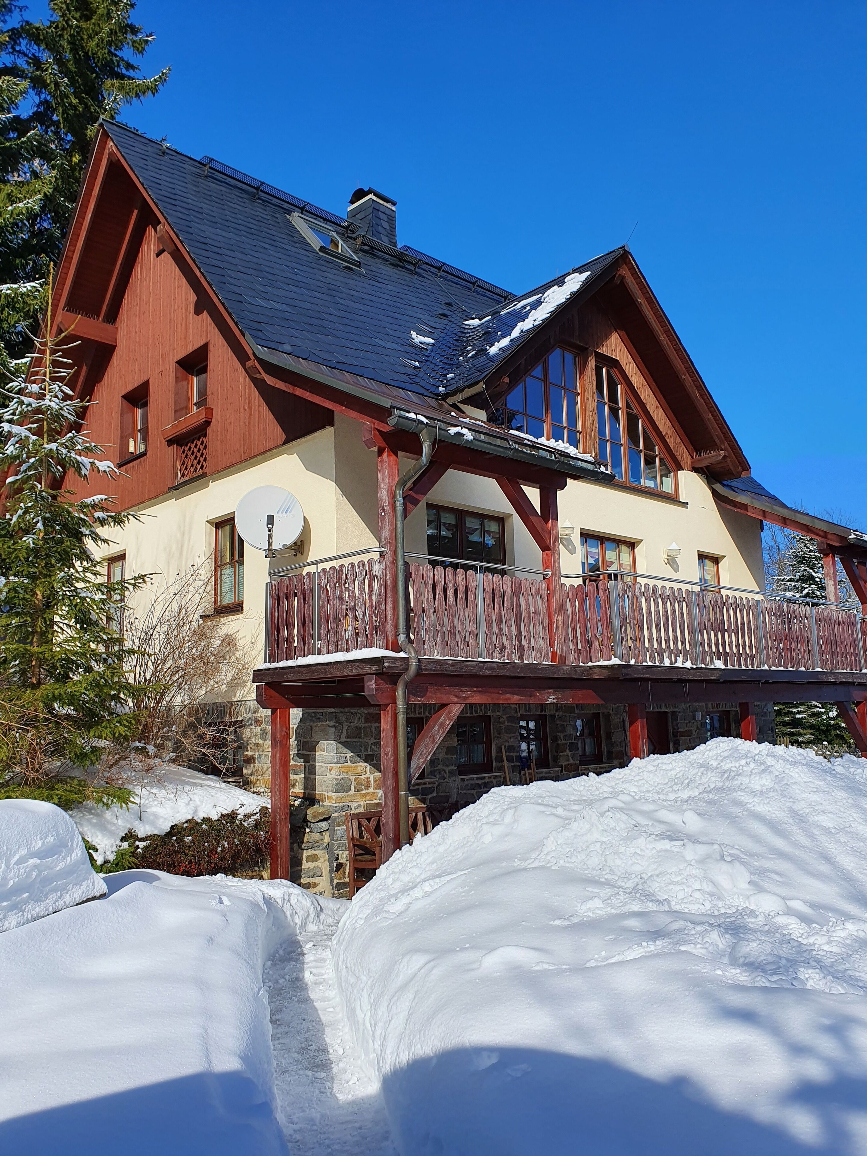 Eine große, zweistöckige Chalet mit Holzbalkon und Stein Fundament.