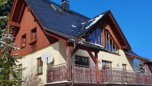 Un chalet grande de dos pisos con balcón de madera y base de piedra.